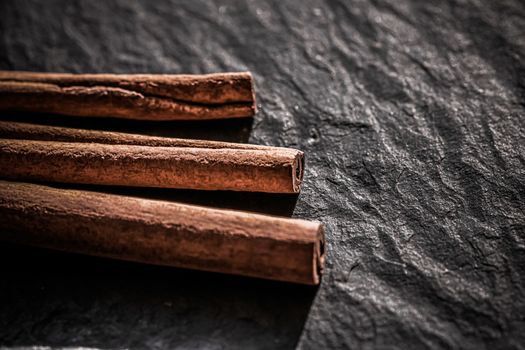 Cinnamon sticks on black stone background, food recipes