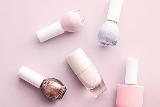 Nail polish bottles on blush pink background, beauty branding