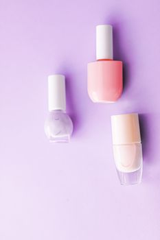 Nail polish bottles on purple background, beauty branding