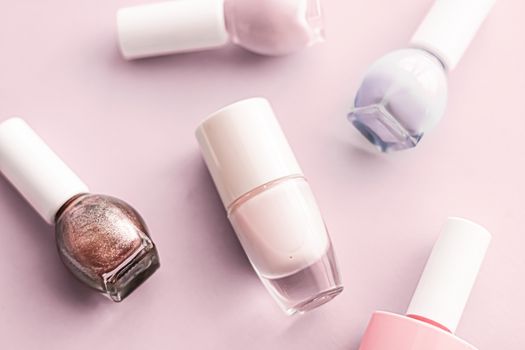 Nail polish bottles on blush pink background, beauty branding