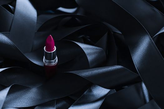 Purple lipstick on black silk background, luxury make-up and beauty cosmetics