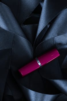 Purple lipstick on black silk background, luxury make-up and beauty cosmetics