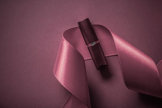 Cosmetic branding, glamour lip gloss and shopping sale concept - Luxury lipstick and silk ribbon on purple holiday background, make-up and cosmetics flatlay for beauty brand product design