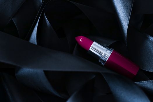 Purple lipstick on black silk background, luxury make-up and beauty cosmetics