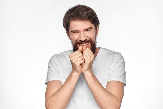 Bearded man in white t-shirt gesture with hands emotions light background. High quality photo