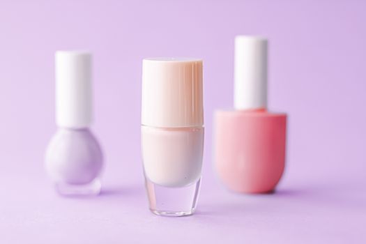 Nail polish bottles on purple background, beauty branding