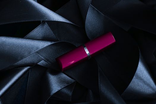 Purple lipstick on black silk background, luxury make-up and beauty cosmetics