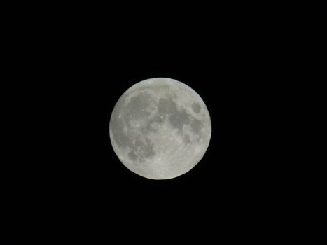 An amazing photography of the full moon over the city of Genova by night with a great clear sky in background and some stars