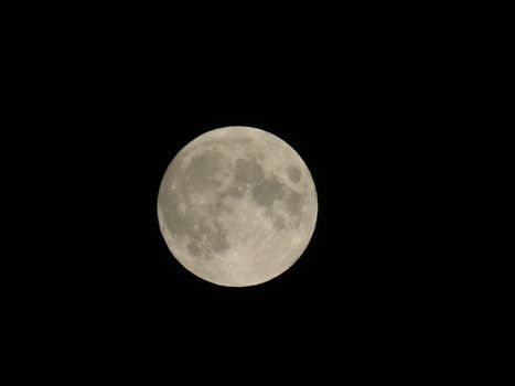 An amazing photography of the full moon over the city of Genova by night with a great clear sky in background and some stars