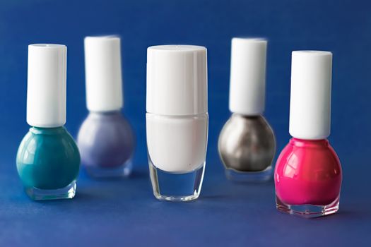 Nail polish bottles on dark blue background, beauty branding