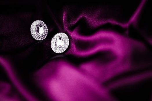 Jewellery brand, elegant fashion and bridal luxe gift concept - Luxury diamond earrings on dark pink silk fabric, holiday glamour jewelery present