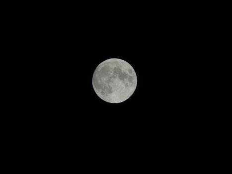 An amazing photography of the full moon over the city of Genova by night with a great clear sky in background and some stars