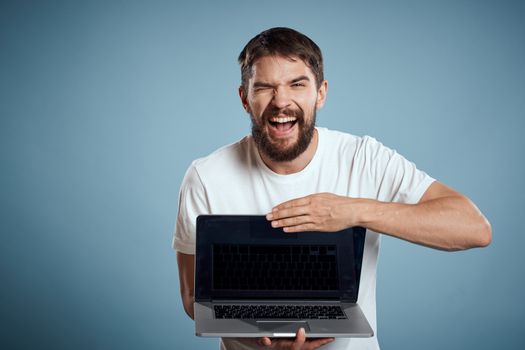 Man shows open laptop keyboard monitor emotions model blue advertising background Copy Space. High quality photo