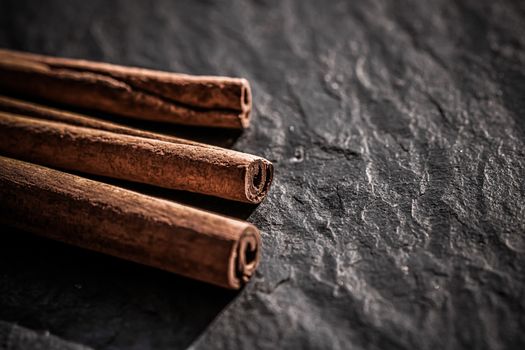 Cinnamon sticks on black stone background, food recipes
