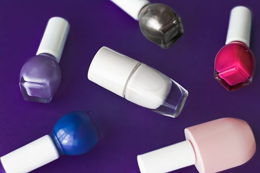 Nail polish bottles on dark purple background, beauty branding