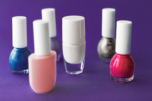 Nail polish bottles on dark purple background, beauty branding