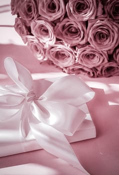 Happy holidays, luxe shopping and love gifts concept - Luxury holiday silk gift box and bouquet of roses on blush pink background, romantic surprise and flowers as birthday or Valentines Day present