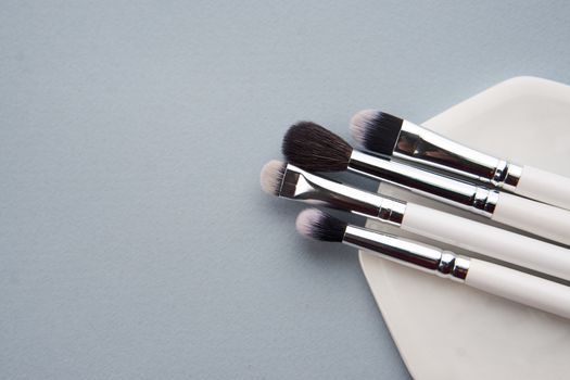 Professional makeup brushes on a white stand on a gray background. High quality photo