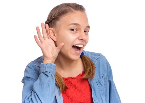 Curious teenage girl placing hand at her ear, having nosy look, isolated on white background