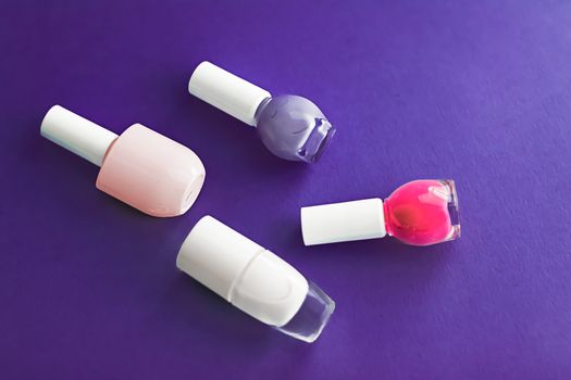 Nail polish bottles on dark purple background, beauty branding