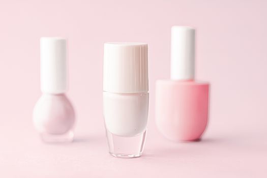 Nail polish bottles on blush pink background, beauty branding