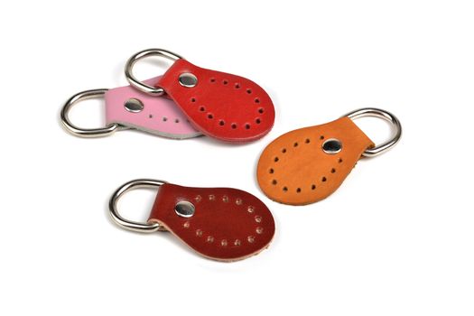 Blank orange pink red brown round color leather key chain collection on isolated white background with clipping path. Pile set of metallic souvenir.