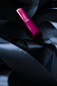 Purple lipstick on black silk background, luxury make-up and beauty cosmetics