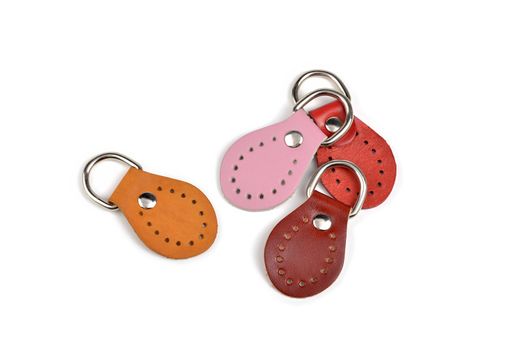 Blank orange pink red brown round color leather key chain collection on isolated white background with clipping path. Pile set of metallic souvenir.