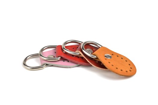 Blank orange pink red brown round color leather key chain collection on isolated white background with clipping path. Pile set of metallic souvenir.