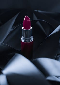 Purple lipstick on black silk background, luxury make-up and beauty cosmetics