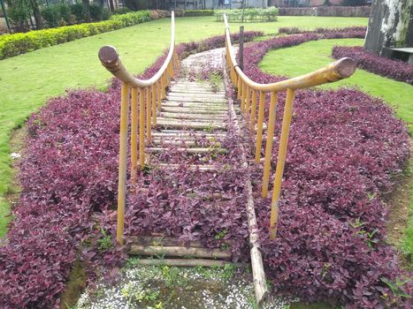 Old iron bridge in the garden with plants and grass.