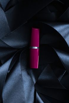 Purple lipstick on black silk background, luxury make-up and beauty cosmetics