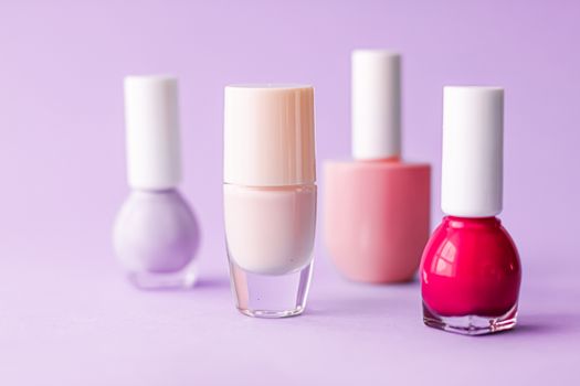 Nail polish bottles on purple background, beauty branding