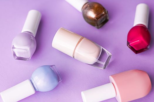 Nail polish bottles on purple background, beauty branding