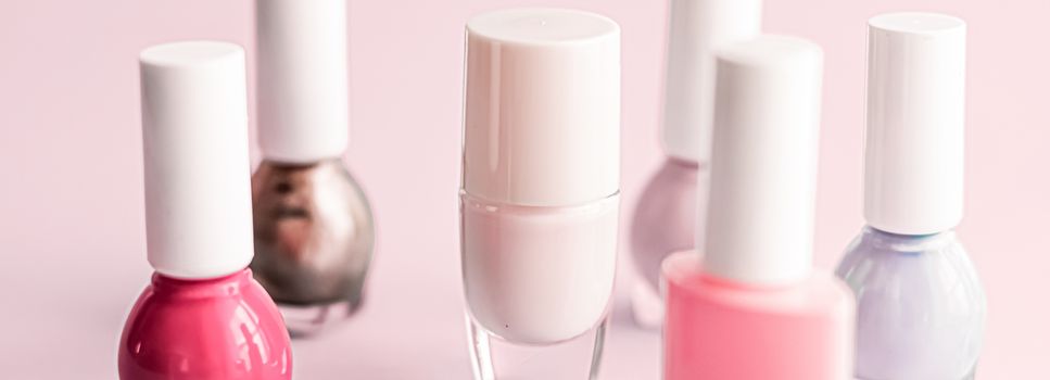 Nail polish bottles on blush pink background, beauty branding