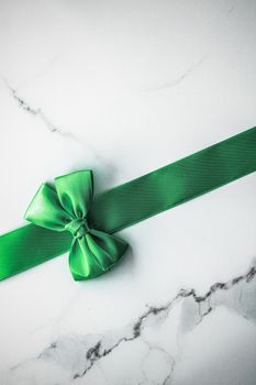 Decorative, birthday and art branding concept - Green silk ribbon and bow on marble background, St Patricks day present or Christmas glamour gift decor for luxury digital brand, holiday flatlay design