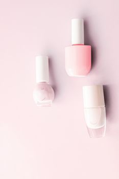 Nail polish bottles on blush pink background, beauty branding