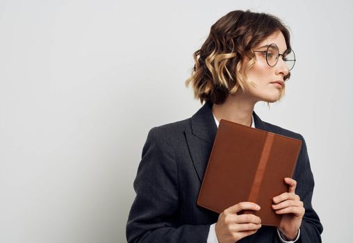 Woman in classic suit with open book glasses on face cropped view on light background. High quality photo