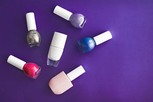 Nail polish bottles on dark purple background, beauty branding