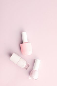 Nail polish bottles on blush pink background, beauty branding