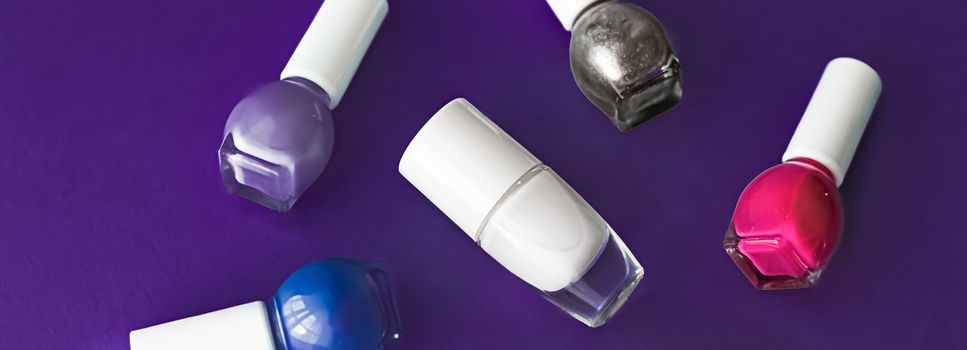 Nail polish bottles on dark purple background, beauty branding