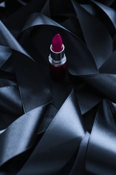 Purple lipstick on black silk background, luxury make-up and beauty cosmetics