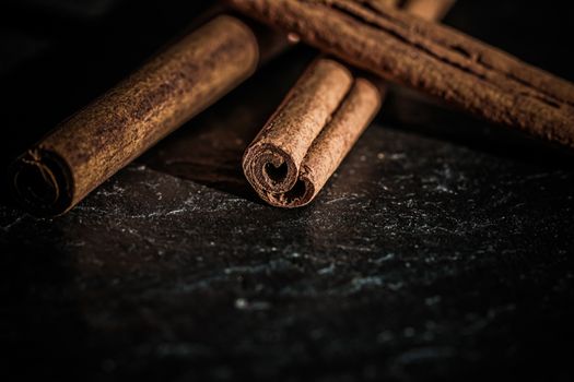 Cinnamon sticks on black stone background, food recipes