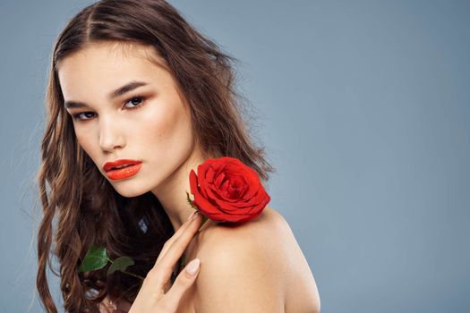 woman with a rose in her hands naked shoulders evening makeup red lips. High quality photo