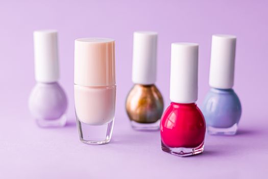 Nail polish bottles on purple background, beauty branding