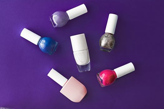 Nail polish bottles on dark purple background, beauty branding