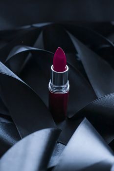 Purple lipstick on black silk background, luxury make-up and beauty cosmetics