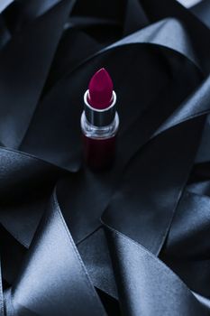 Purple lipstick on black silk background, luxury make-up and beauty cosmetics