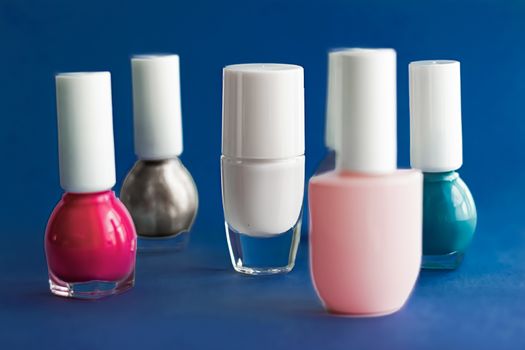 Nail polish bottles on dark blue background, beauty branding