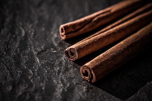 Cinnamon sticks on black stone background, food recipes